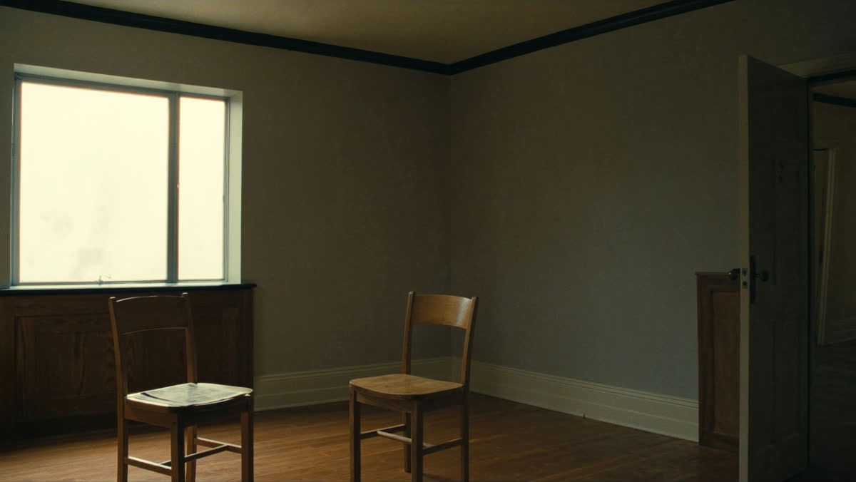 Two empty wooden chairs turned toward each other in a quiet church side room