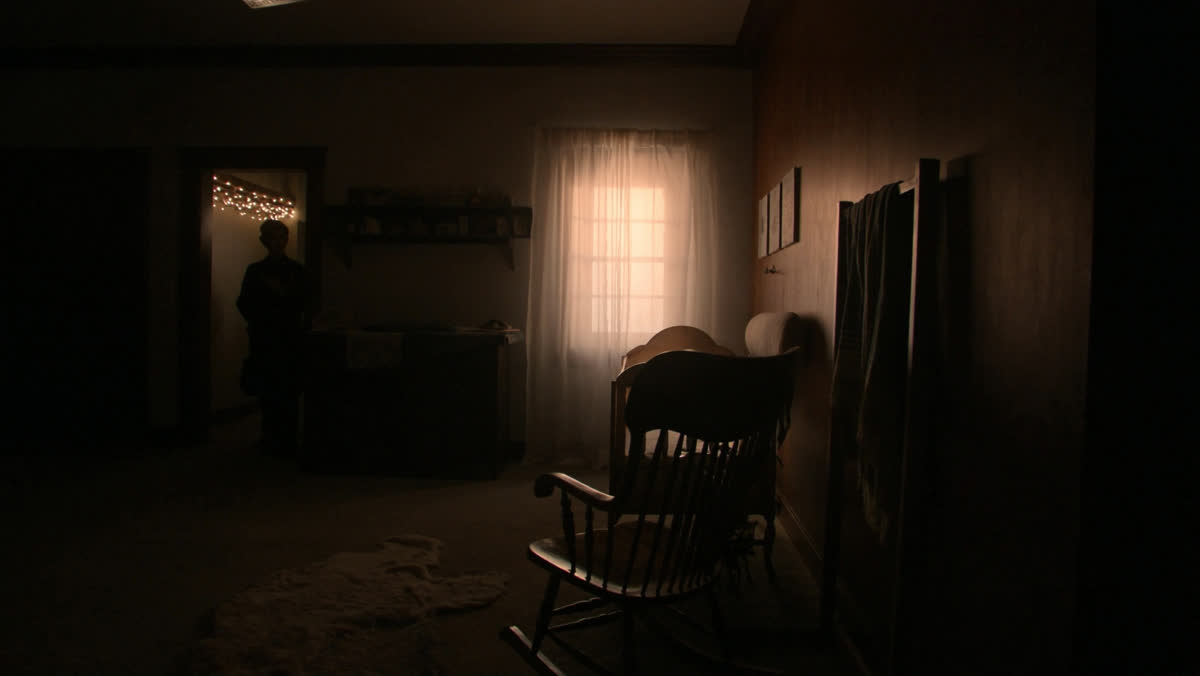 A softly lit nursery corner at dawn with a wooden rocking chair and folded blanket