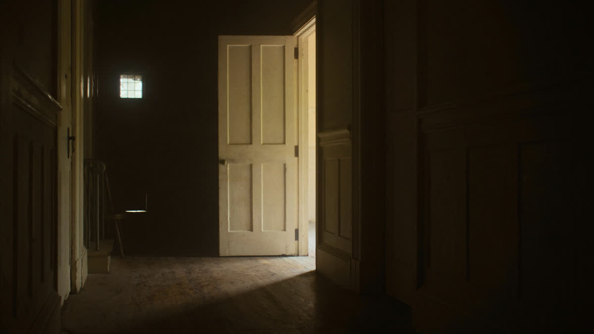 An open door at the end of a church hallway with warm light spilling onto the floor